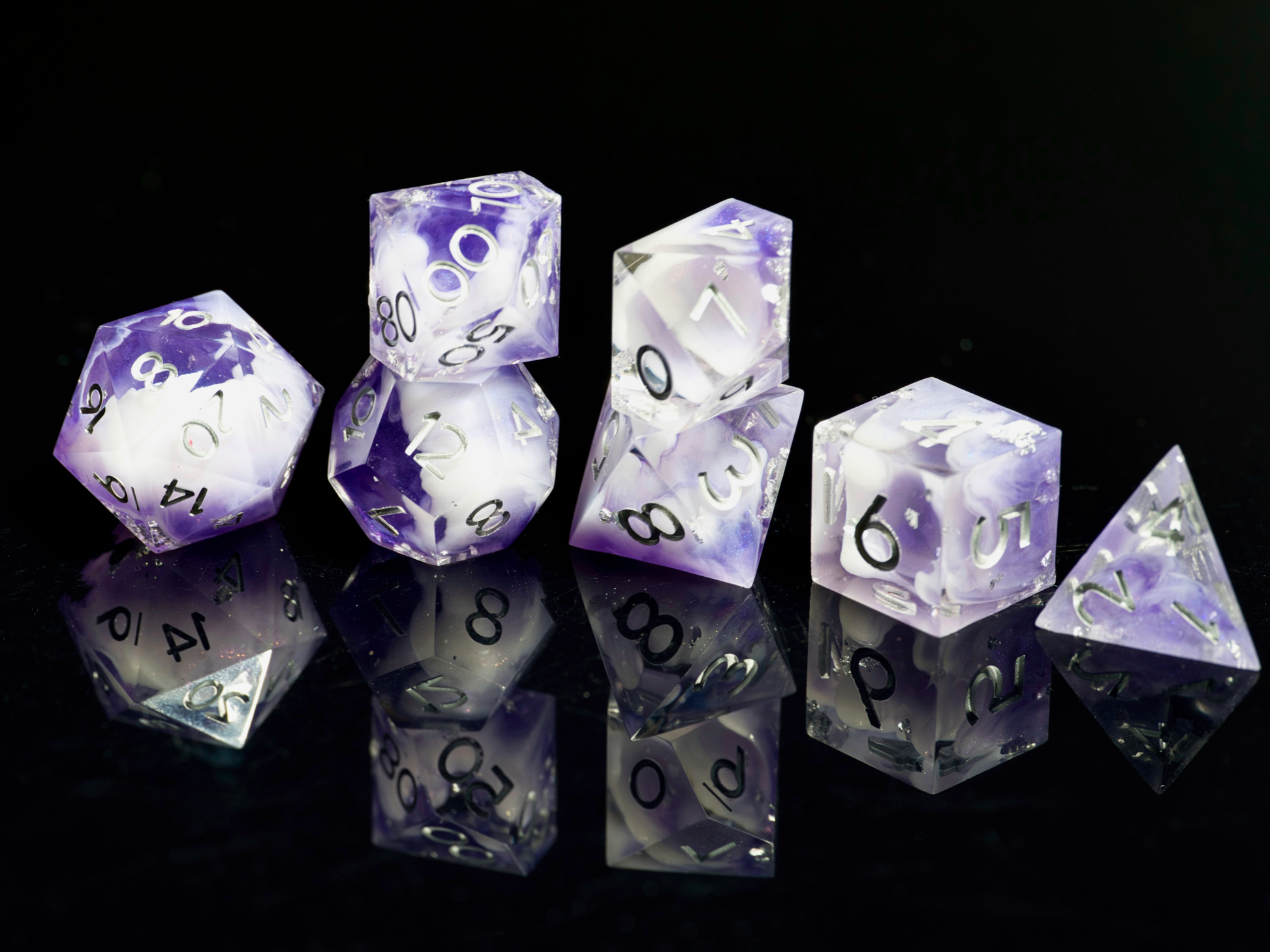 Set of purple and clear polyhedral dice on a black background